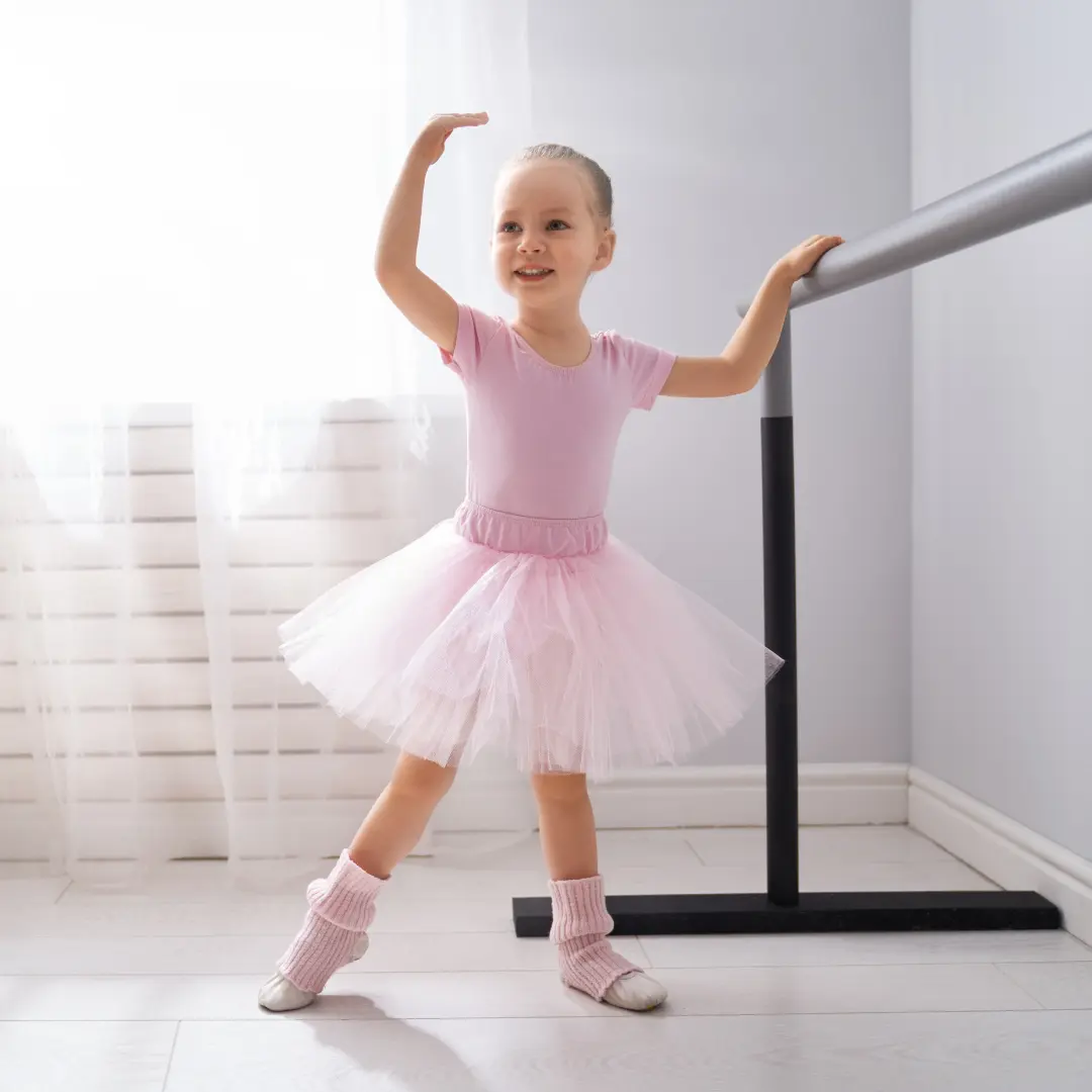 Kleine Tänzerin in Ballettkleidung macht erste Übungen an der Stange
