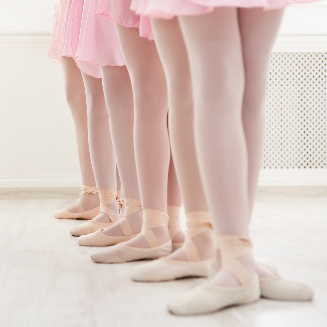 Foto-Shot auf die Füße mehrerer Kinder im Ballettkurs für Kinder ab 3, die hintereinander in einer Reihe stehen