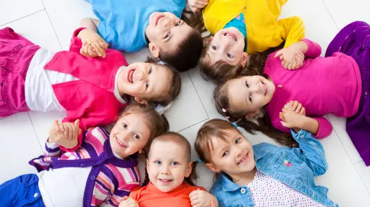 Lachende Kleinkinder liegen im Kreis am Boden - Symbolbild für Kindertanzkurs für 3- bis 5-Jährige
